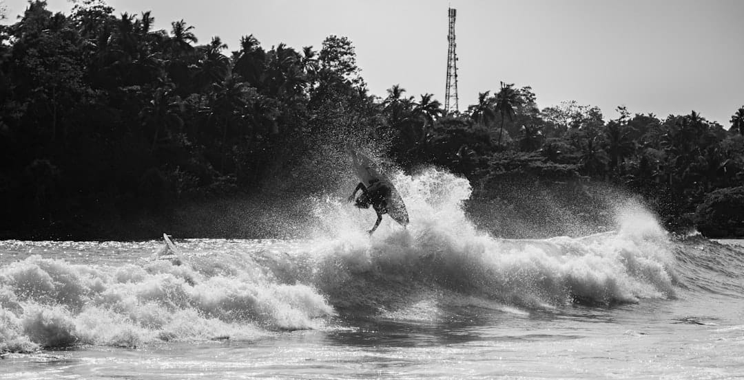 A surfer performs a dramatic aerial maneuver.