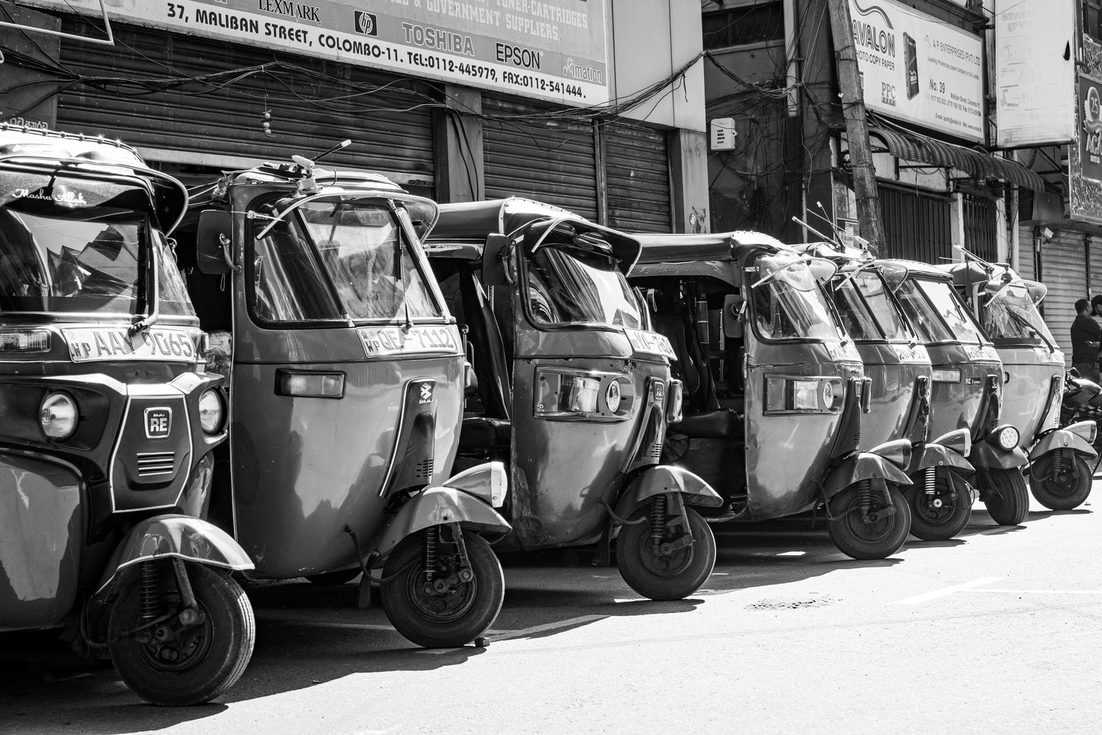 Black and white photo of tuk-tuks parked in Colombo, Sri Lanka's bustling street.